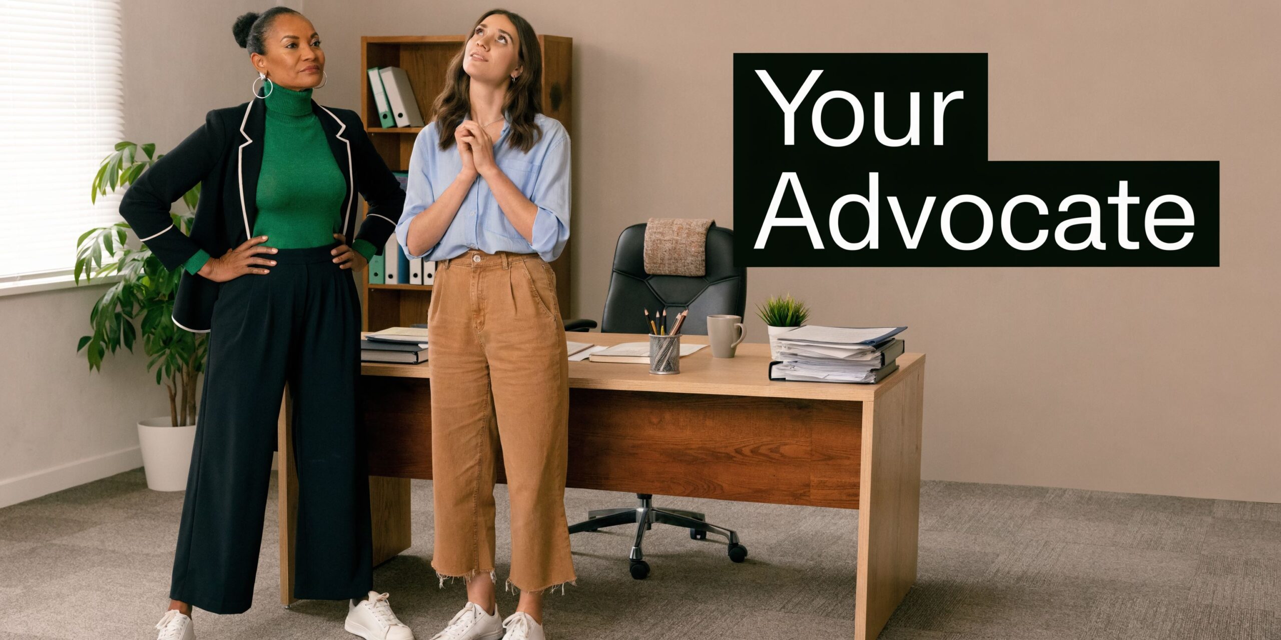 A professional woman in a blazer and a young woman standing together in a bright office setting.
