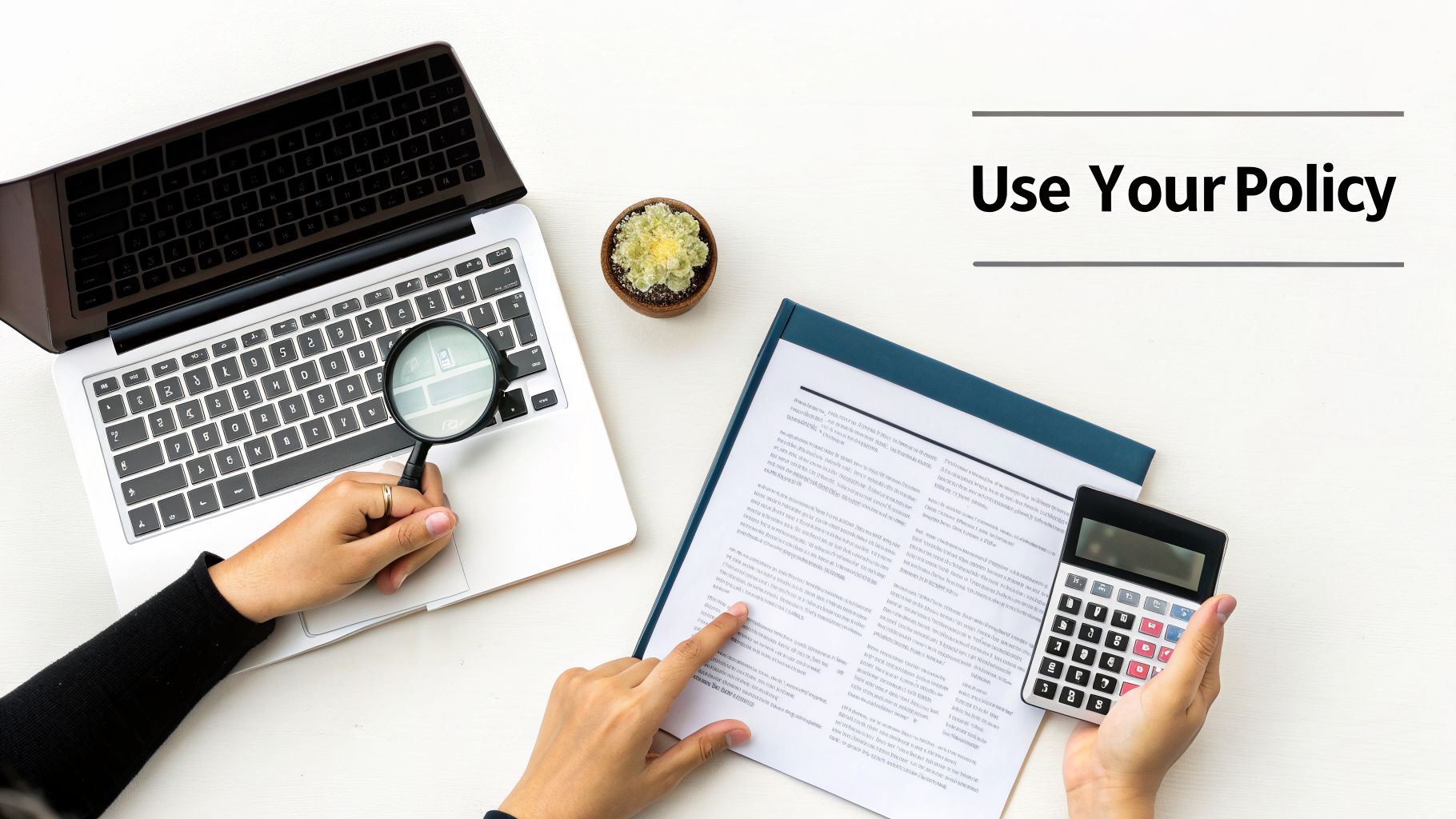 A person reviews a policy document with a calculator, laptop, and magnifying glass on a white desk.