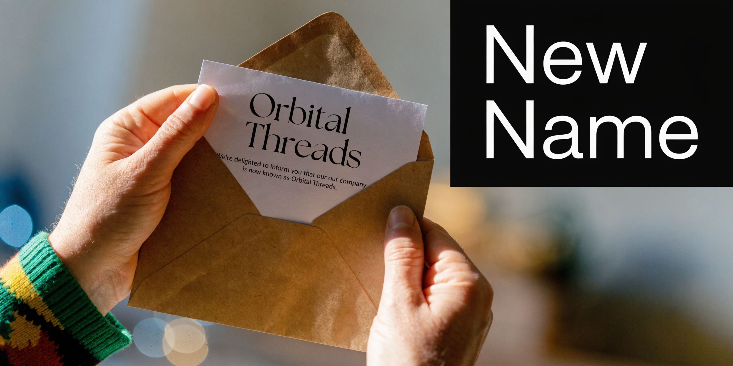A person holding an envelope with a note announcing the name change to Orbital Threads company.